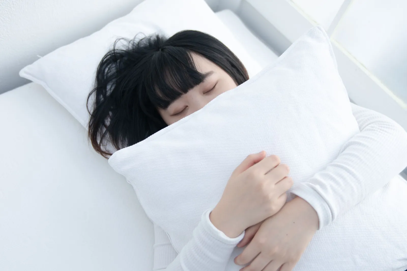 xSleepの上で枕を抱いて寝ているイメージ写真