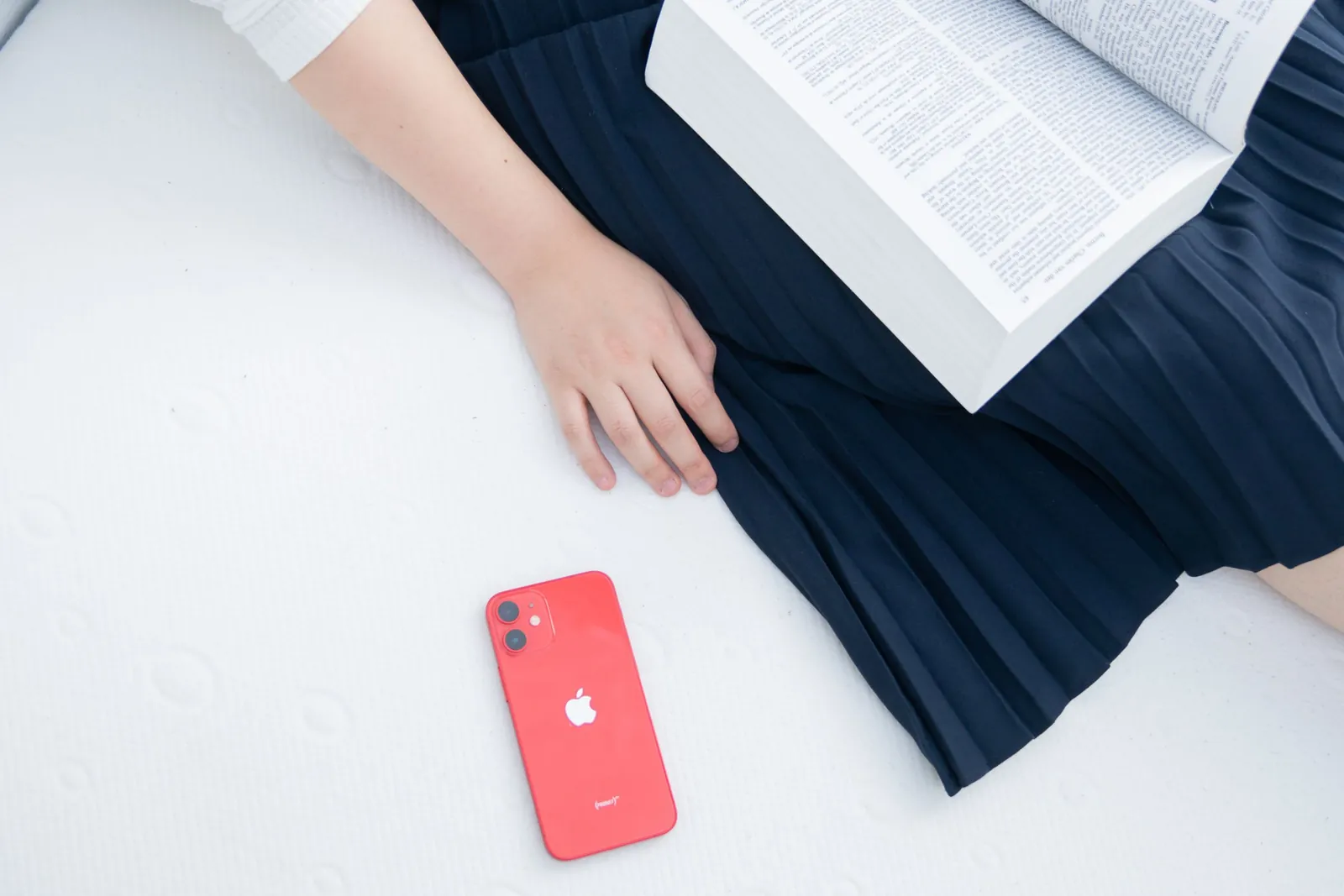 パーソナライズドマットレスのxSleepの上でスマホを横に置いて本を読んでいる写真